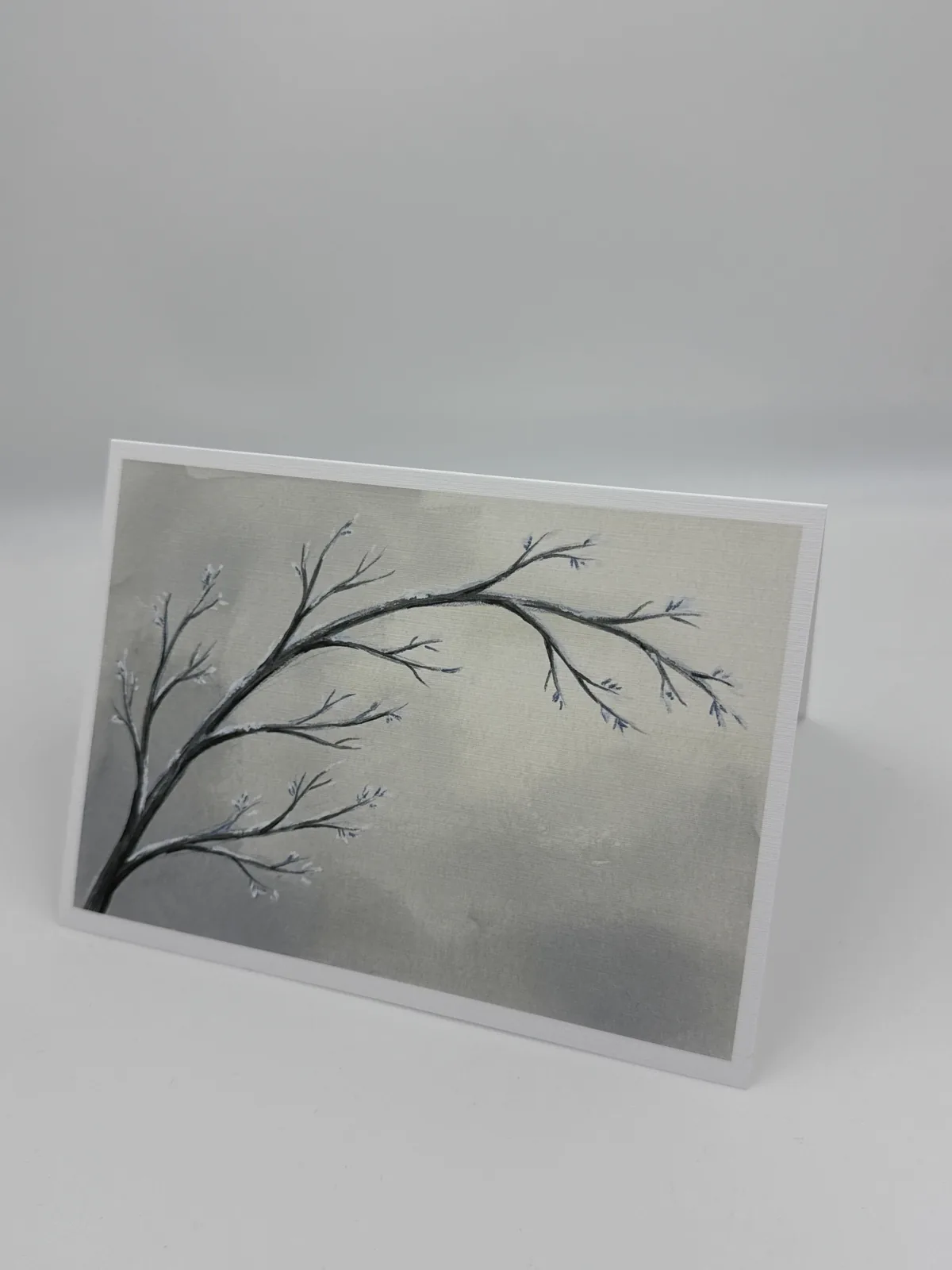 A sympathy card showing a delicate frost-covered branch against a soft gray sky