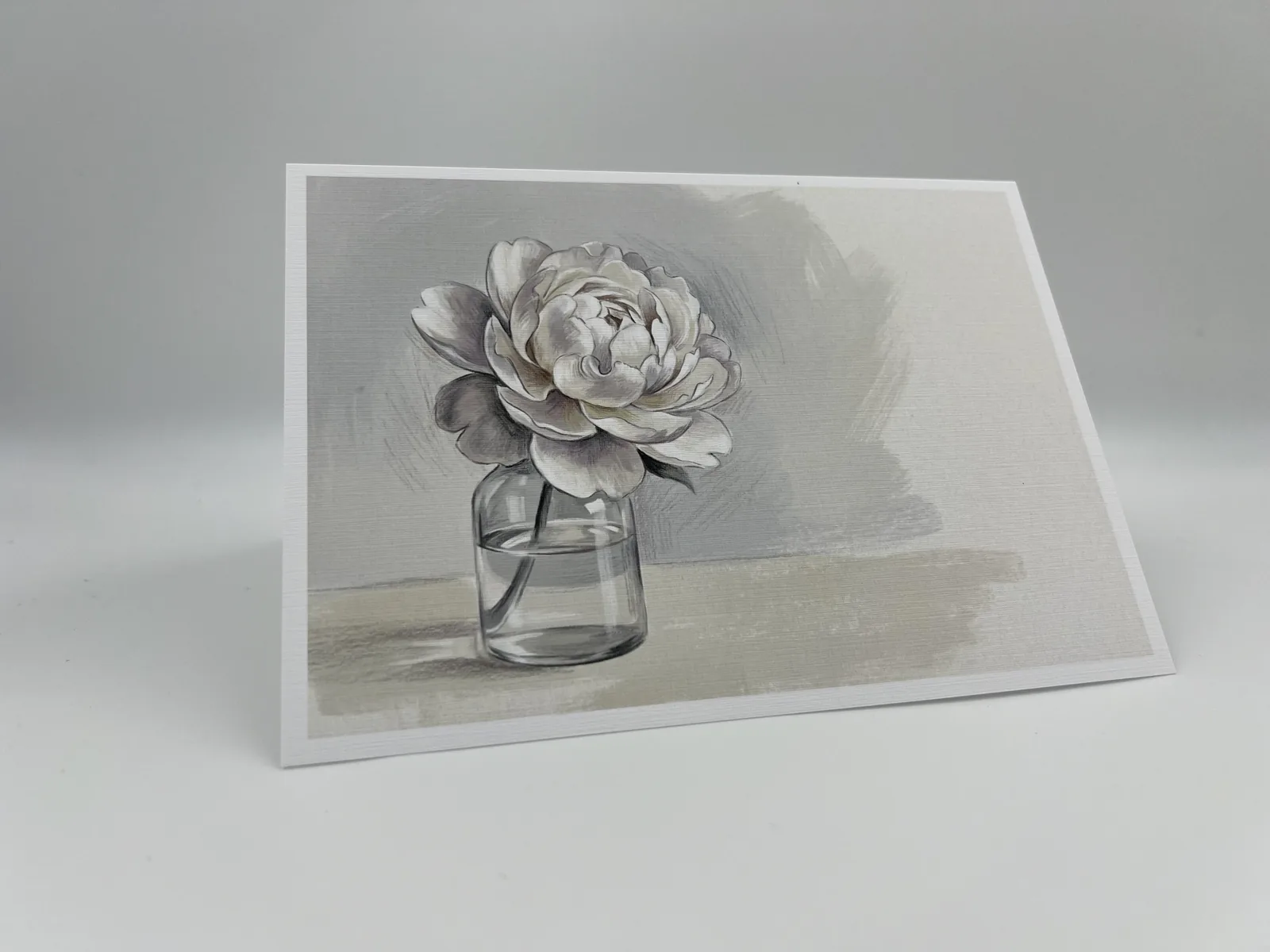 A sympathy card featuring a softly painted white peony resting in a small glass vase