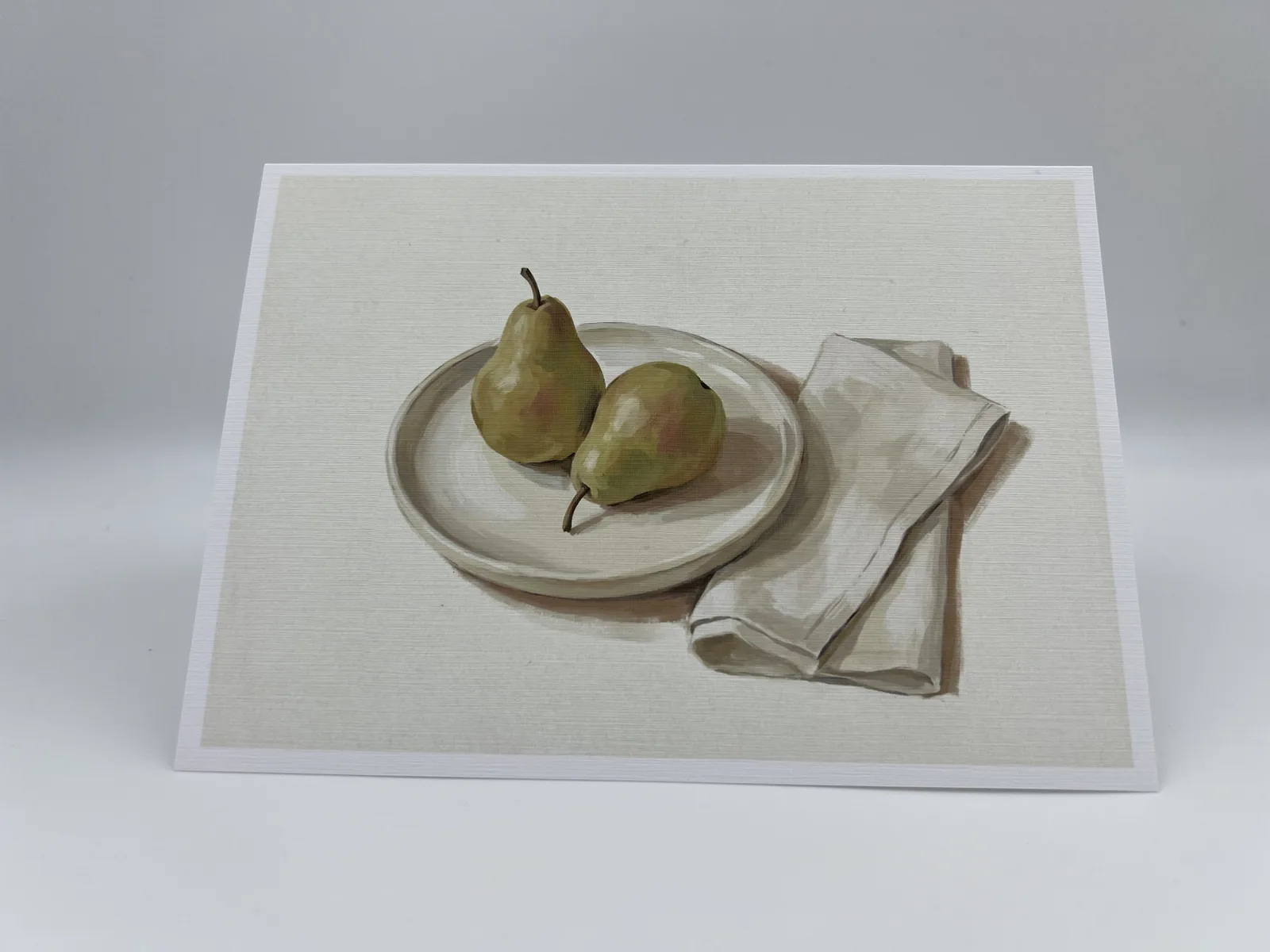 A wedding thank-you card with a still-life painting of two pears on a plate beside a linen napkin